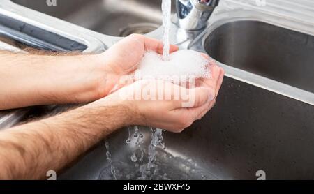 L'uomo lava le mani nel lavandino metallico con sapone. Uomo caucasico lavarsi le mani. Concetto sanitario di igiene e disinfezione delle mani. Banner Web lungo Foto Stock