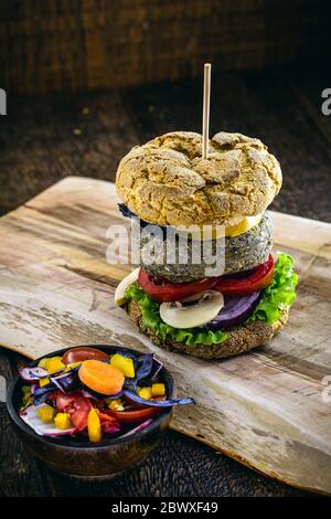 Hamburger gustoso e vegano di riso e verdure, su rustico sfondo di legno. Alimenti vegani senza carne o prodotti animali. Foto Stock