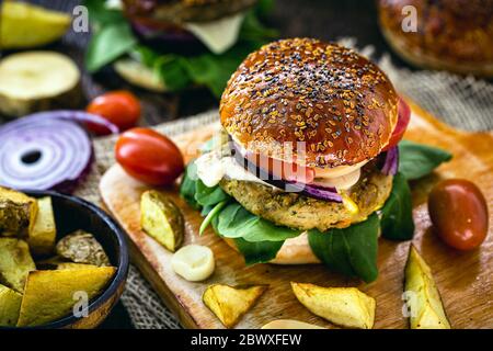 Hamburger vegano, panino fatto senza carne, con bicchiere di succo verde sullo sfondo. Insaporire con pepe, funghi, pomodoro, lattuga e proteine Foto Stock