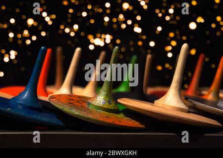 Vista frontale sui colorati giocattoli in legno dipinti a mano - pioli o vorticosi come sfondo creativo per il tuo design con luce bokeh sfocata oro Foto Stock