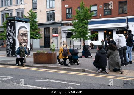 Manchester, Regno Unito. 3 Giugno 2020. Alcuni membri del pubblico che prendono il ginocchio sono visti da un murale di George Floyd, l'uomo nero di 46 anni, morto a Minneapolis, Minnesota il 25 maggio dopo che Derek Chauvin, un ufficiale bianco con il Dipartimento di polizia di Minneapolis, ha premuto il ginocchio al collo di Floyd, Manchester, Regno Unito. Credit: Jon Super/Alamy Live News. Foto Stock