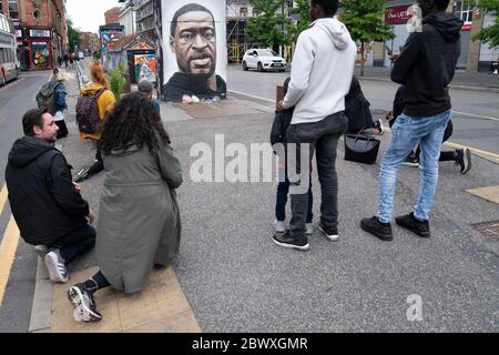 Manchester, Regno Unito. 3 Giugno 2020. Alcuni membri del pubblico che prendono il ginocchio sono visti da un murale di George Floyd, l'uomo nero di 46 anni, morto a Minneapolis, Minnesota il 25 maggio dopo che Derek Chauvin, un ufficiale bianco con il Dipartimento di polizia di Minneapolis, ha premuto il ginocchio al collo di Floyd, Manchester, Regno Unito. Credit: Jon Super/Alamy Live News. Foto Stock