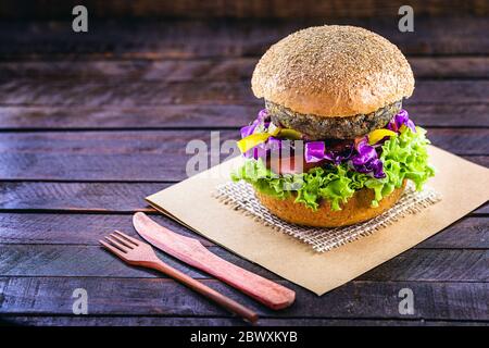 hamburger vegetariano, arrosto e pronto per il consumo. Concetto di vita sana e vegetariana. Spuntino senza carne a base di soia e ceci con cubetti di legno Foto Stock