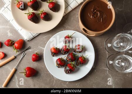 Composizione con fonduta di cioccolato su tavola grigia. Cibo dolce delizioso Foto Stock