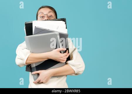 Una giovane donna e un gran numero di documenti di lavoro. Lavoratore in ufficio occupato Foto Stock