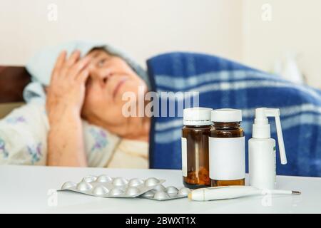 Una donna anziana a letto, davanti a lei sul tavolo sono farmaci, davanti a lei sul tavolo sono farmaci Foto Stock