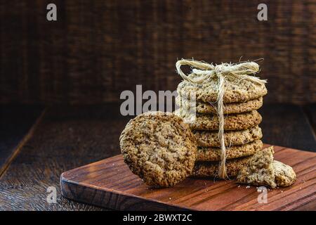 Biscotti interi a grani con cereali, frutta secca e cioccolato su vecchio tavolo di legno Foto Stock