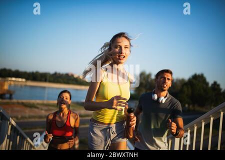 Fitness, sport, persone ed esecuzione di concetto. Montare felici amici correndo all'aperto Foto Stock