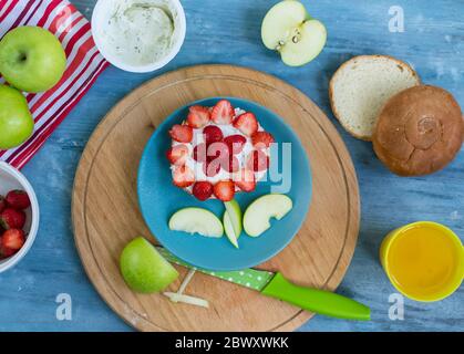 Il cibo è divertente per i bambini. Il sandwich è a forma di fiore di fragole per la colazione dei bambini. Semplice ricetta dettagliata per cucinare piatti per il menu. Fe Foto Stock