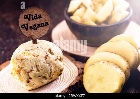 Pane di formaggio vegano, senza prodotti di origine animale, con ingredienti sul lato, tapioca e patate. Segno di legno con iscrizione: Vita vegana. Foto Stock