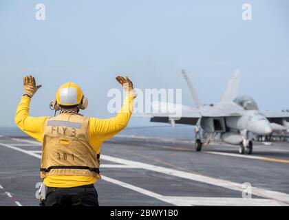 Segnali della giacca gialla della marina degli Stati Uniti alle navi che comandano ufficiali Capt. J.J. Cummings, che atterra il suo F/A-18F Super Hornet sul ponte di volo della compagnia di aerei della classe Ford USS Gerald R. Ford 15 maggio 2020 nell'Oceano Atlantico. Foto Stock