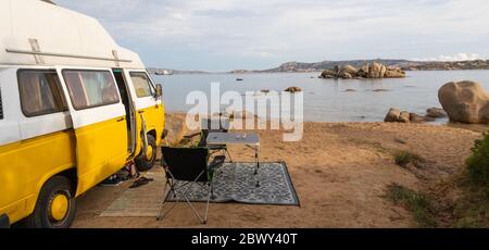 Vecchio colorato camper retrò sul campeggio in un bellissimo paesaggio roccioso costiero della Costa Smeralda, nord-est della Sardegna, Italia. Turismo vacanza e. Foto Stock