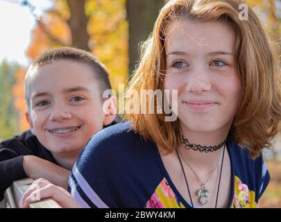 Teen Brother e Suor in Park on Bench in autunno con i colori giallo brillante e blu scuro nella contea di Lancaster, Pennsylvania Foto Stock