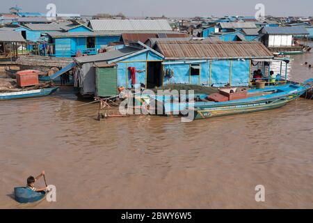 Il ragazzo pagaia intorno villaggio galleggiante sul lago Tonle SAP vicino a Siem Reap, Cambogia Foto Stock