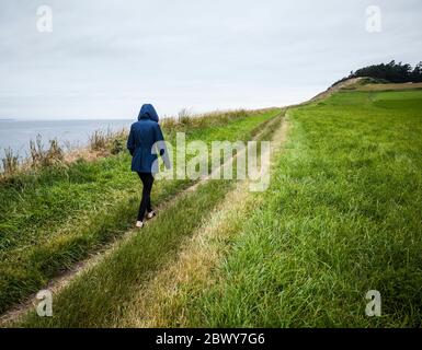 Una giovane donna che cammina lungo il sentiero per Ebeys Bluffs, Ebey's Landing National Historical Reserve, Whidbey Island, Washington, USA. Foto Stock