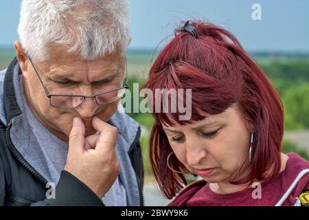 Un uomo e una coppia sposata stanno guardando le informazioni che sono arrivate sul suo telefono cellulare. Foto Stock