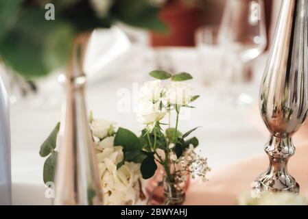 Festoso tavolo decorazione floreale. Rose bianche sul tavolo con panno da tavolo bianco. Concetto di celebrazione, compleanno e matrimonio. Foto Stock