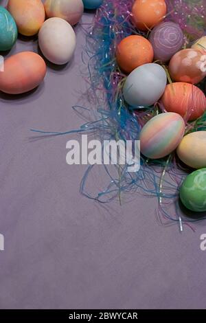 tinte uova di pasqua raccolte su un tavolo con colorata erba di pasqua plastica Foto Stock