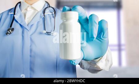 Foto di un medico in uniforme con stetoscopio che contiene una bottiglia di plastica pillole. Foto Stock