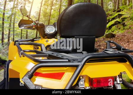 Foto di un veicolo atv giallo fuoristrada in piedi nella vista posteriore ravvicinata della foresta. Foto Stock