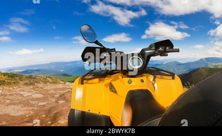 Foto di un veicolo atv giallo fuoristrada in piedi su una vista del volante di un sentiero in montagna. Foto Stock