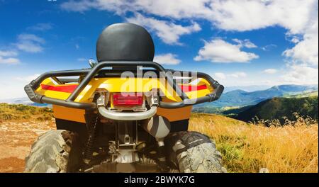 Foto di un veicolo atv giallo fuoristrada in piedi su una vista posteriore di un sentiero in montagna. Foto Stock