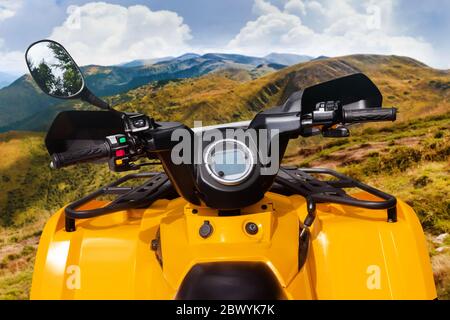 Foto di un veicolo atv giallo fuoristrada in piedi su una vista ravvicinata del volante di un sentiero in montagna. Foto Stock