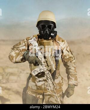 Foto di un soldato completamente attrezzato in uniforme, armatura, casco e maschera a gas in piedi con fucile in campo di battaglia deserto vista frontale sfondo. Foto Stock