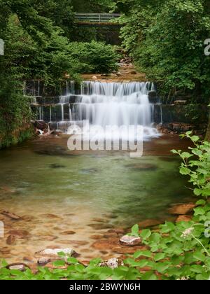 Cascata del fiume gerês che corre tra gli alberi prima di cadere gettare i gradini di roccia ed entrare nel villaggio Foto Stock