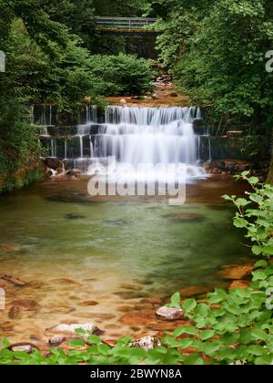 Cascata del fiume gerês che corre tra gli alberi prima di cadere gettare i gradini di roccia ed entrare nel villaggio Foto Stock