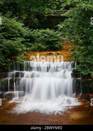 Cascata del fiume gerês che corre tra gli alberi prima di cadere gettare i gradini di roccia ed entrare nel villaggio Foto Stock