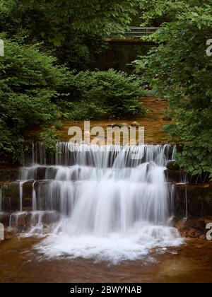 Cascata del fiume gerês che corre tra gli alberi prima di cadere gettare i gradini di roccia ed entrare nel villaggio Foto Stock