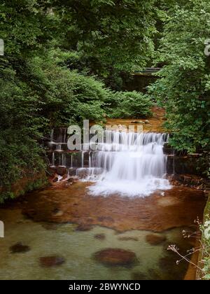 Cascata del fiume gerês che corre tra gli alberi prima di cadere gettare i gradini di roccia ed entrare nel villaggio Foto Stock