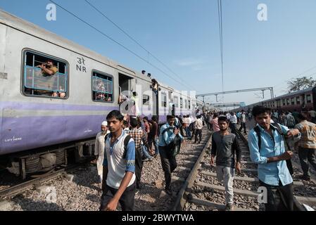 I pendolari si aggirano tra le ferrovie e si siedono sul tetto di un treno sovraffollato delle ferrovie indiane, alla stazione ferroviaria di Noli vicino a Ghaziabad, Nuova Delhi, in Foto Stock