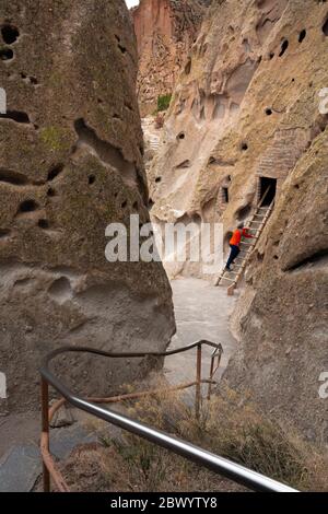 NM00462-00...NUOVO MESSICO - visitatore del parco che guarda una dimora sulla scogliera vista dal percorso Loop Trail al Bandelier National Monument. Foto Stock