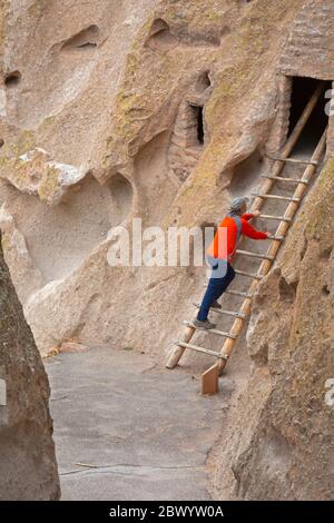 NM00463-00...NUOVO MESSICO - visitatore del parco che guarda una dimora sulla scogliera vista dal percorso Loop Trail al Bandelier National Monument. Foto Stock