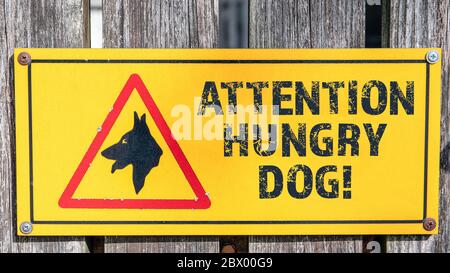 ATTENZIONE CANE AFFAMATO. Cartello di avvertimento, area privata, sicurezza e forze dell'ordine. Informazioni con una battuta alla recinzione di legno Foto Stock