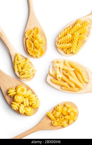 Vari tipi di pasta italiana cruda in cucchiai di legno isolati su fondo bianco. Foto Stock