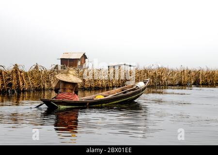 Africa, Africa occidentale, Benin, Lago Nokoue, Ganvié. Donna che canottava sul retro di una piroga fuori dalla città sul lago di Ganvié sul lago Nokoue. Foto Stock