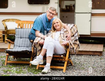 Famiglia matura riposante su sedie a sdraio vicino camper in campagna Foto Stock