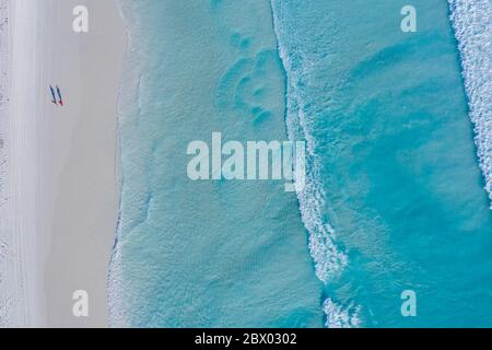 Vista panoramica di due persone che camminano lungo la spiaggia di Lucky Bay vicino alle acque turchesi dell'Australia occidentale Foto Stock