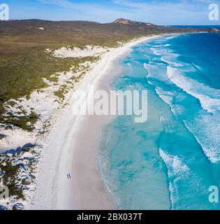 Vista aerea di tre quarti di due persone che camminano lungo la spiaggia di Lucky Bay vicino alle acque turchesi limpide dell'Australia Occidentale Foto Stock