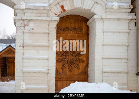 La porta gialla della casa rurale con sculture in legno nel villaggio russo. Foto Stock