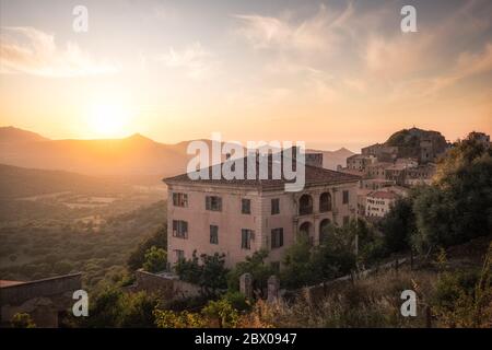 Sole che si affaccia sull'antico villaggio di montagna di Belgodere nella regione Balagne della Corsica con il mare Mediterraneo in lontananza Foto Stock