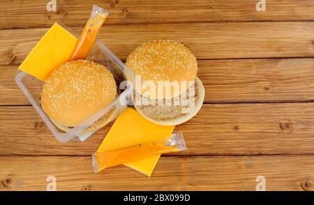 Due hamburger di manzo al forno a microonde con formaggio e salsa su sfondo di legno Foto Stock