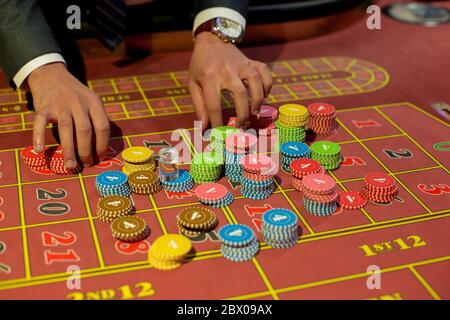 Casino chip sfondo. Il concessionario ha le mani con i chip. Chip casinò sul tavolo da gioco. Foto Stock