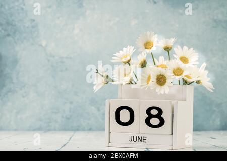 Calendario cubo bianco per giugno decorato con fiori margherita su sfondo blu con spazio copia Foto Stock