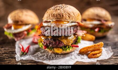 Menu di hamburger gustosi e succosi con hamburger di manzo doppio sul davanti con spicchi di patate e peperoncino e altri due hamburger sul retro Foto Stock