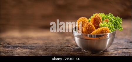 Bocconcini di pollo con insalata in una ciotola di metallo su una superficie rustica di legno Foto Stock