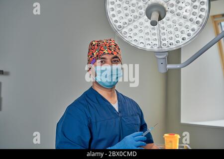 un chirurgo mascherato contro una lampada nella sala operatoria Foto Stock